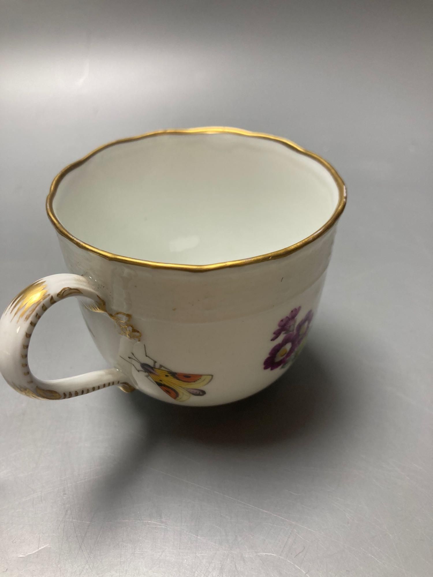 A Meissen cup and saucer, factory seconds, decorated with fruit and butterflies and lined with gilt